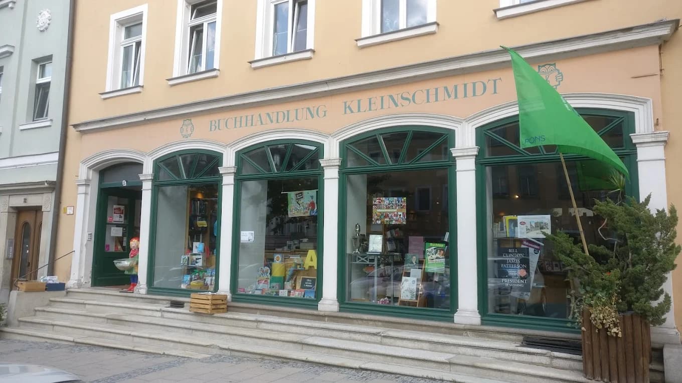 Schaufenster der Buchhandlung Kleinschmidt in Hof, Bayern. Eine ansprechend beige Fassade, mit grünen Akzenten und großen Fenstern, für eine tolle Leseathmosphäre und Leseerlebnis.